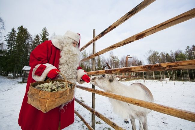 Papá Noel alimentando a un pequeño reno 